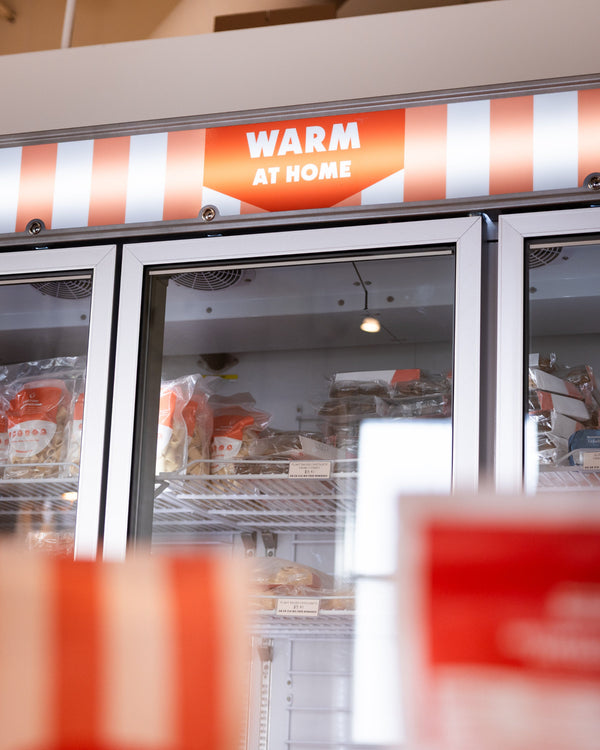 Frozen food display case with 'Warm at Home' sign above it