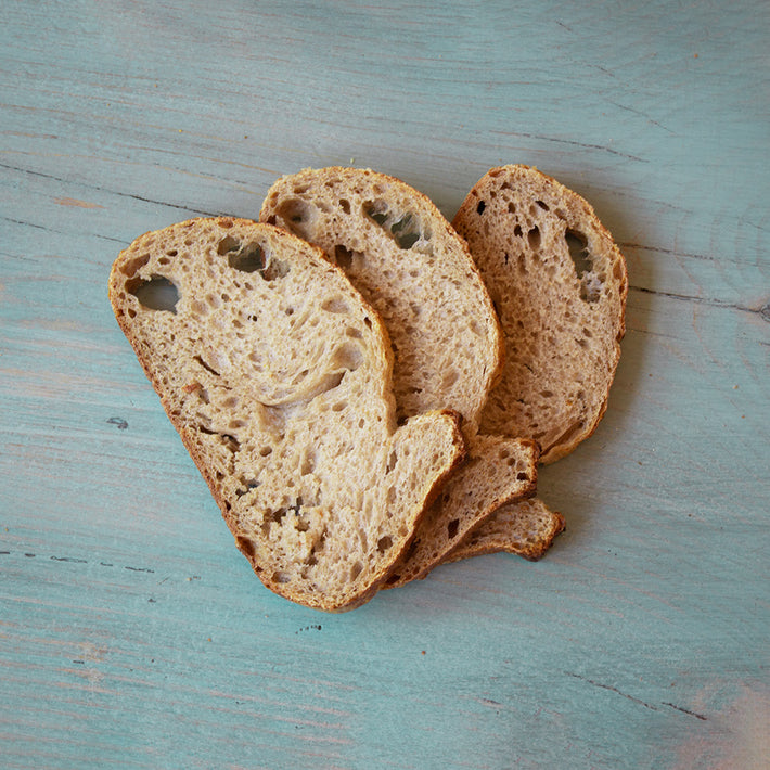 Three slices of sourdough whole wheat bread on a blue surface