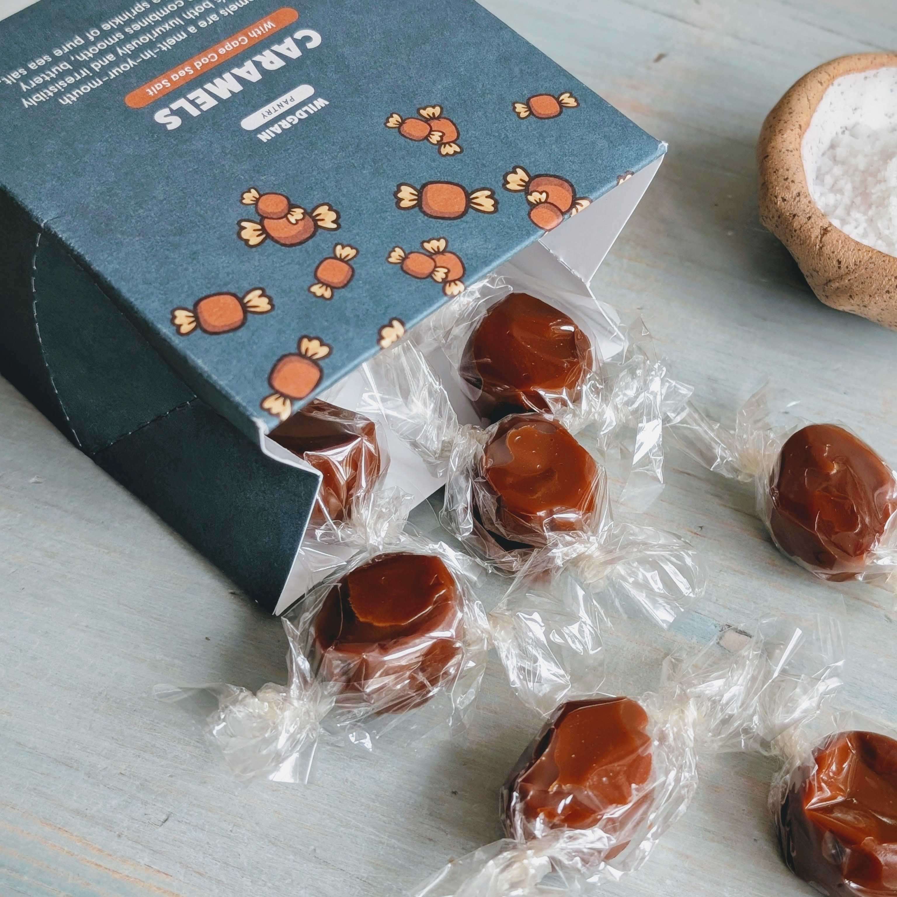 Wrapped sea-salt caramels spilling from a blue box labeled CARAMELS