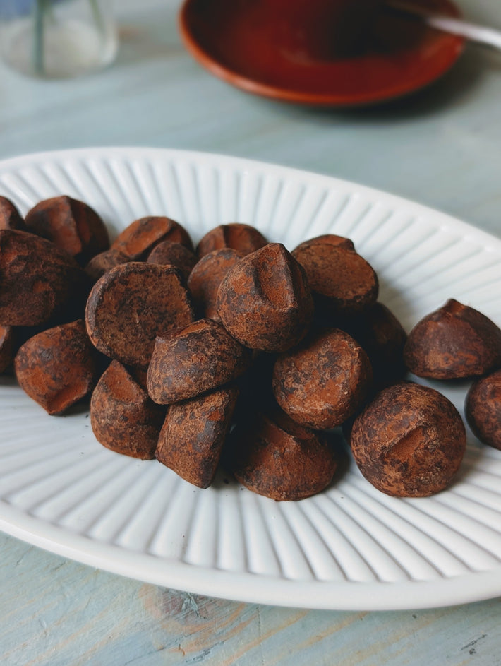 Chocolate truffles dusted in cocoa, piled on a white fluted plate
