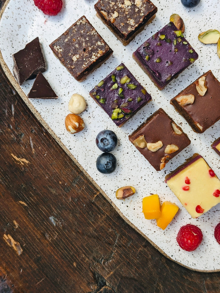 A variety of chocolate squares with nuts and berries on a plate