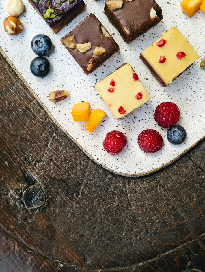 Assorted desserts including chocolate squares, fruits, and nuts on a plate