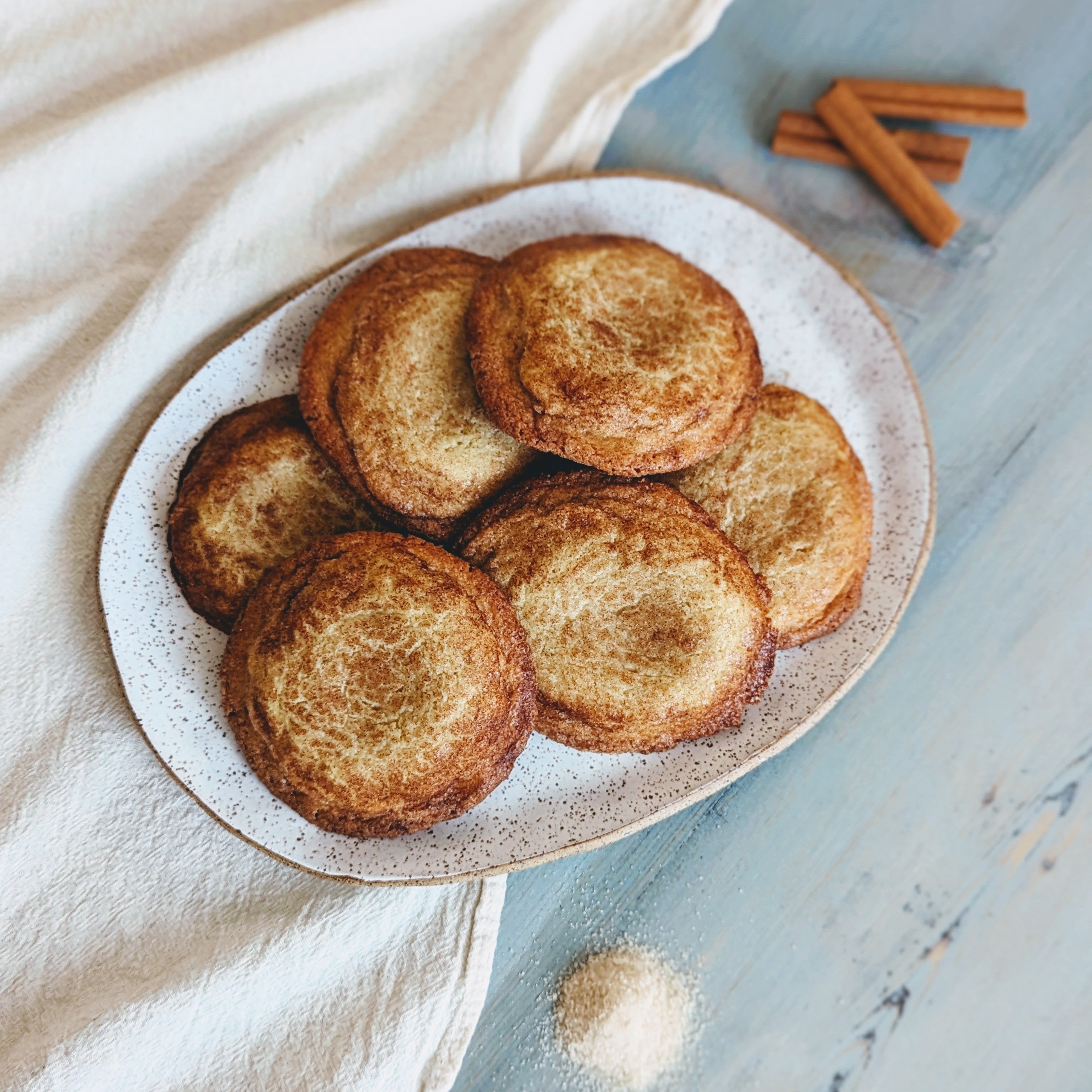 Giant Snickerdoodle Cookies on a plate with cinnamon sticks and sugar