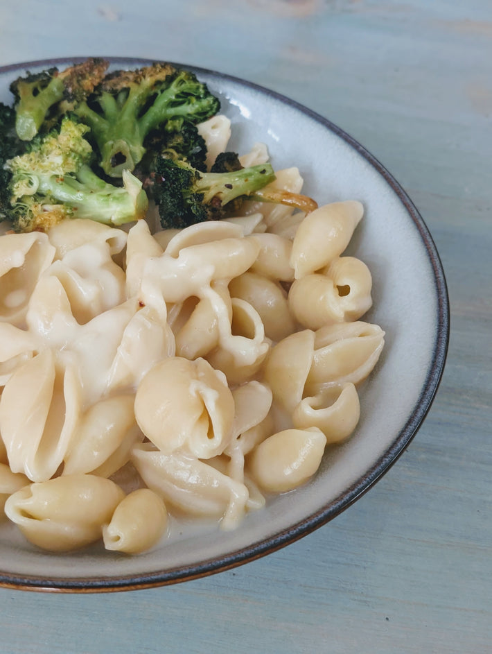 Creamy pasta with shell shapes and roasted broccoli in a bowl.