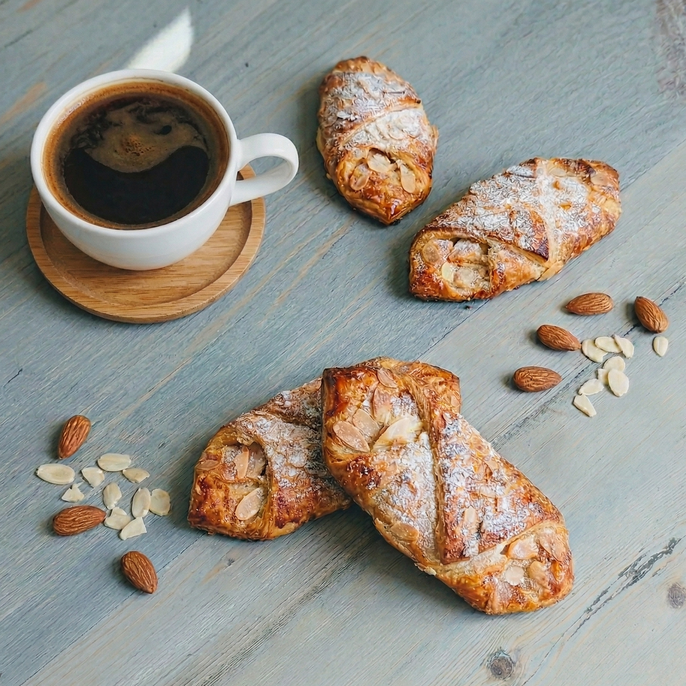 Cup of coffee with croissants and almonds on a wooden surface