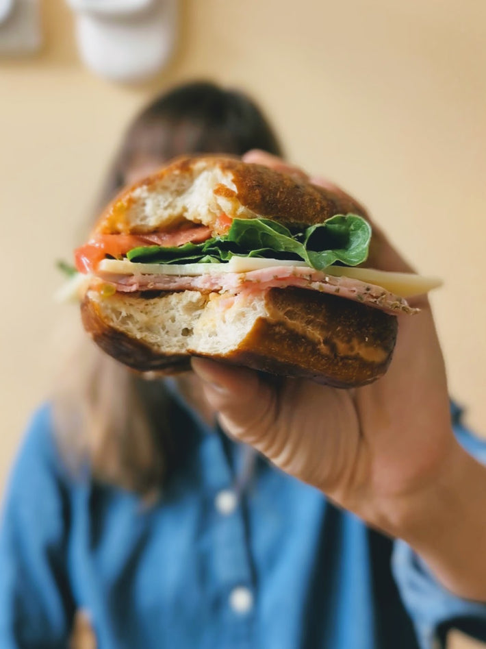 Bavarian Pretzel Bun sandwich with ham, cheese, lettuce, and tomato.
