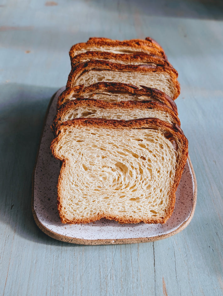 Sliced Croissant Loaf on a speckled plate against a light blue wooden surface.