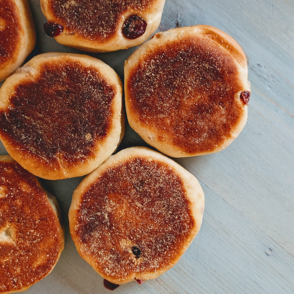 Five jam-filled sugar-coated doughnuts arranged on a blue wooden surface