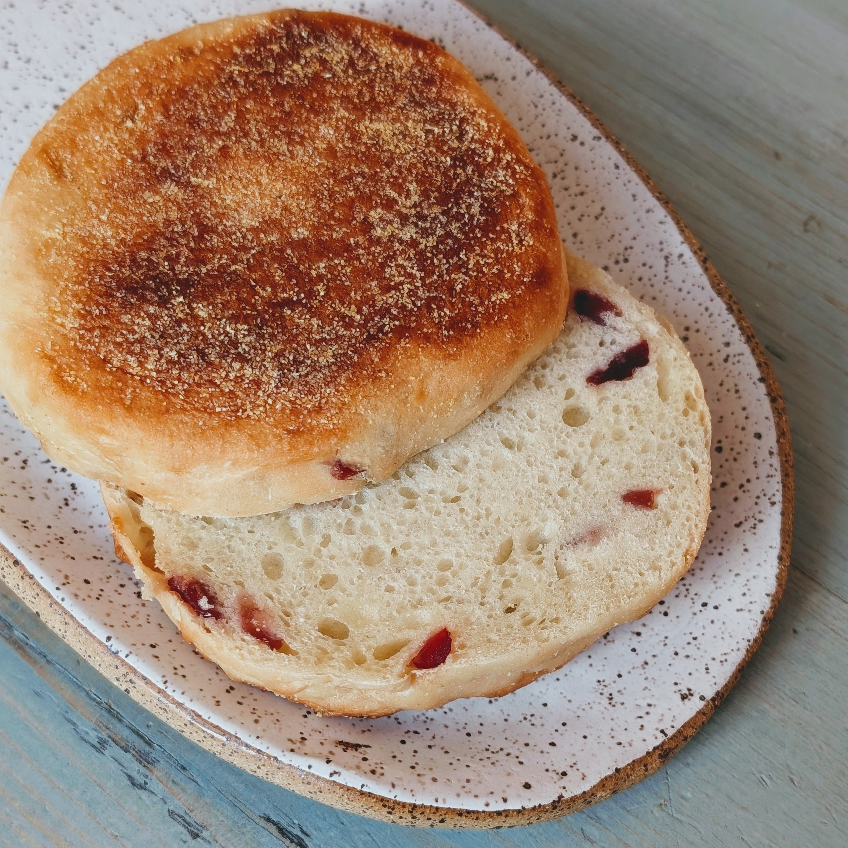 Toasted cranberry English muffin split on a speckled ceramic plate