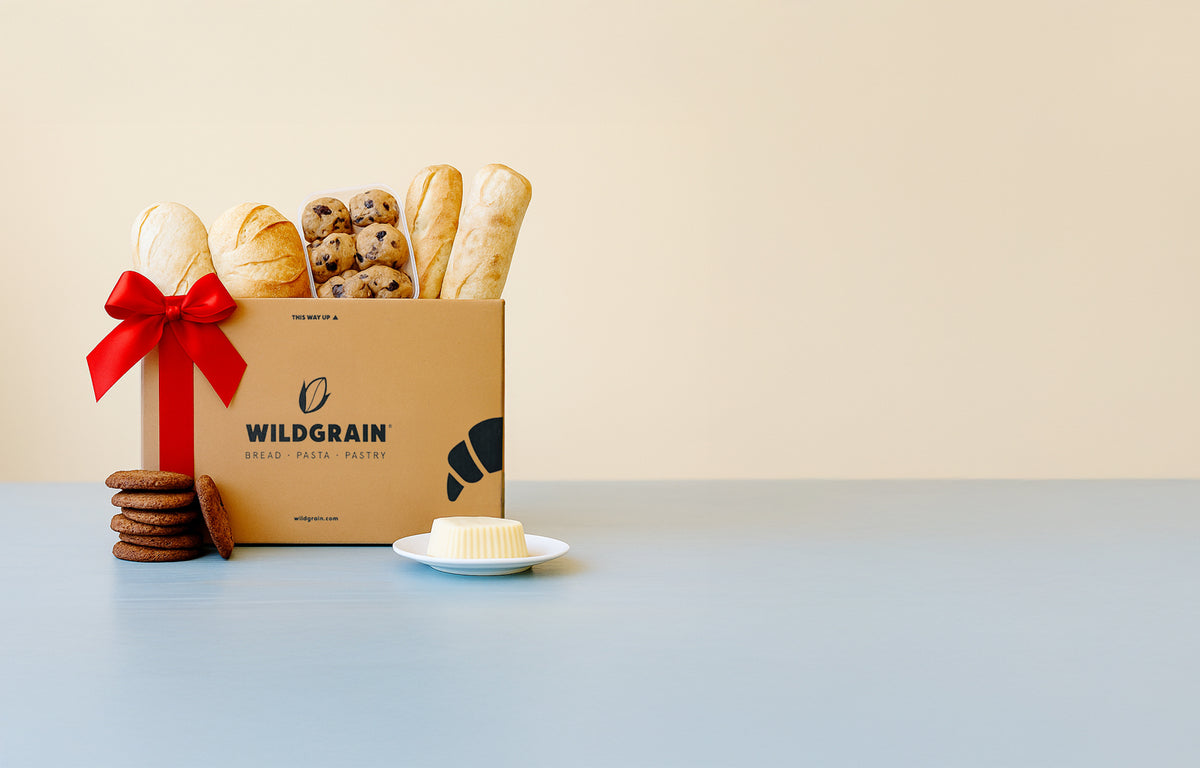Bread gift box with cookies and butter on a table, decorated with a red ribbon for corporate gifting