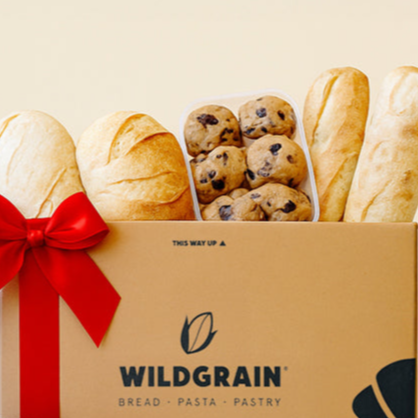 Gift box from Wildgrain with bread, pastries, and cookies on a light yellow background