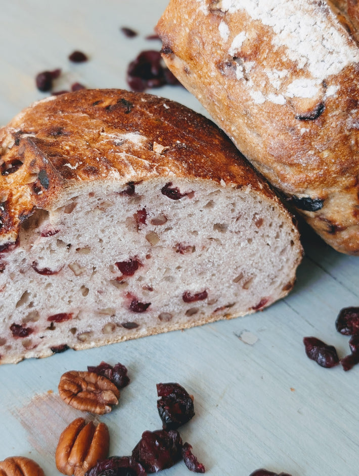 Loaf of bread with dried fruits and nuts on a light blue surface