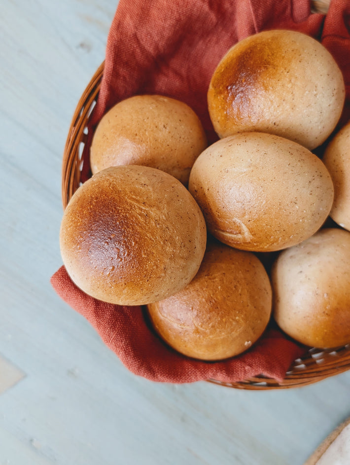 Close-up of round dinner rolls in a wicker basket lined with red cloth.