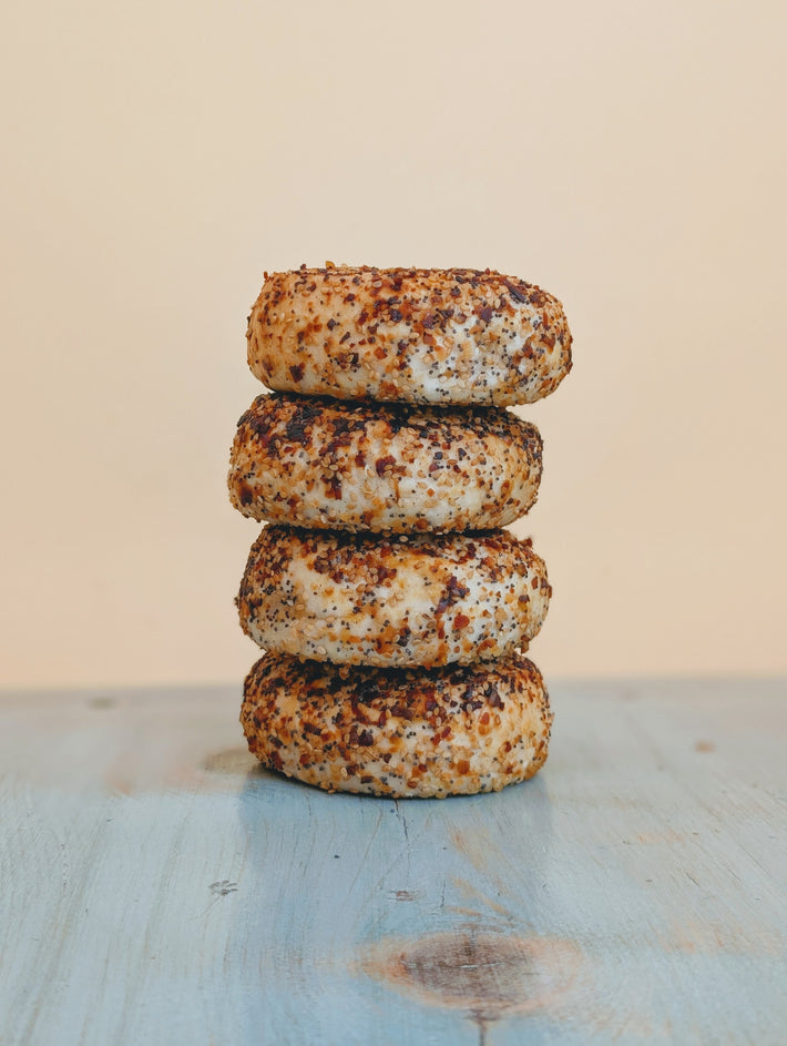 Stack of four everything bagels with crispy, seasoned crust and visible seeds and spices.