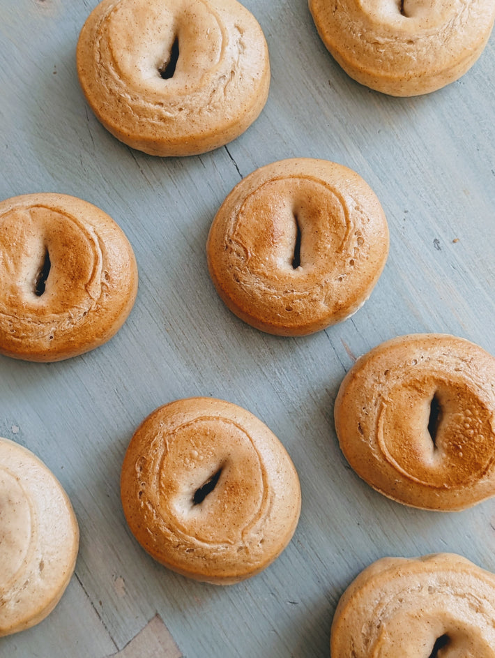 Plain bagels on a light-blue wooden surface, arranged loosely.