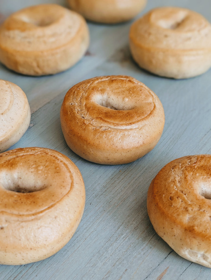 Several plain golden-brown bagels arranged on a light-blue wooden surface.