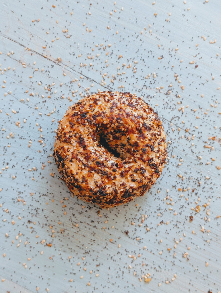 Toasted everything bagel with sesame seeds on a blue surface