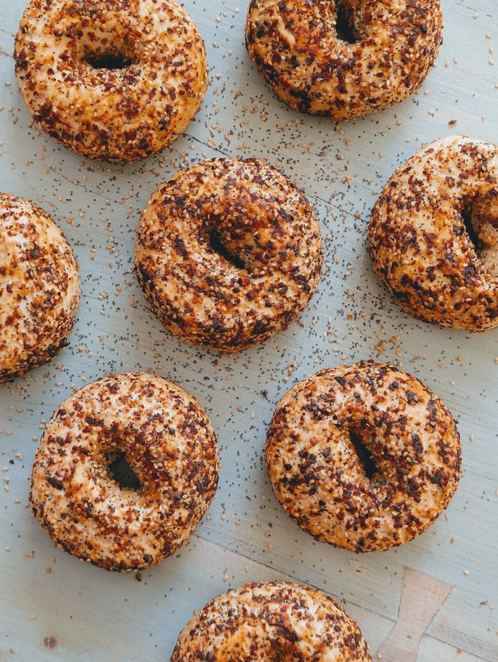 Wildgrain Gluten-Free Everything Bagels with a crunchy topping on a wooden surface.
