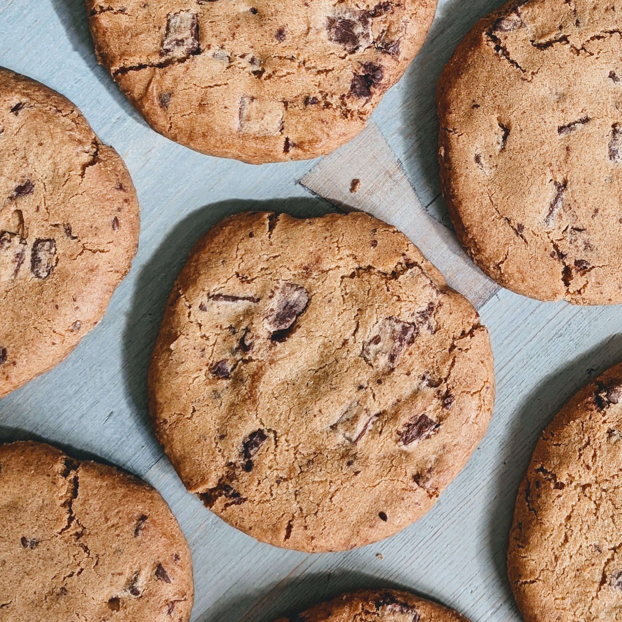 Chocolate chip cookies on a blue wooden board, close-up, seven cookies arranged irregularly