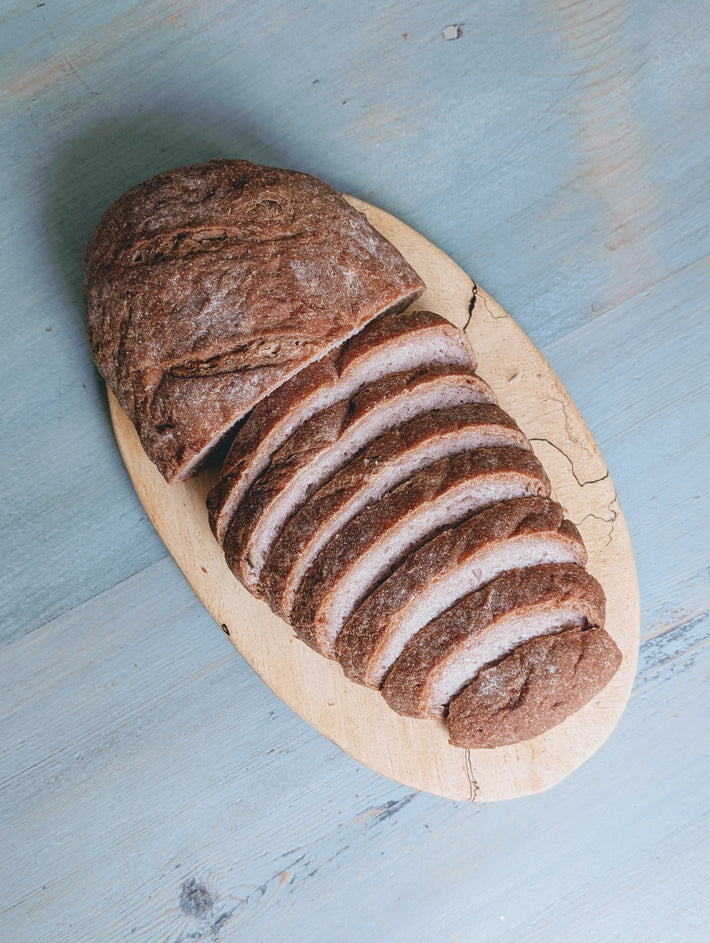 Sliced Gluten-Free Country Loaf on a wooden cutting board, showing its crusty exterior and soft interior.