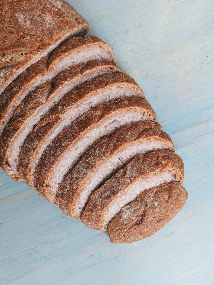 Gluten-Free Country Loaf, sliced, on a light blue surface, showing soft interior.
