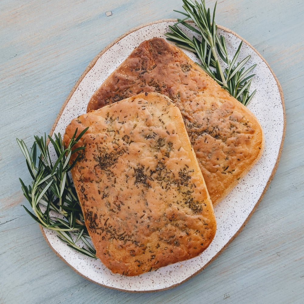 Two pieces of Wildgrain gluten-free focaccia bread garnished with rosemary on a plate.