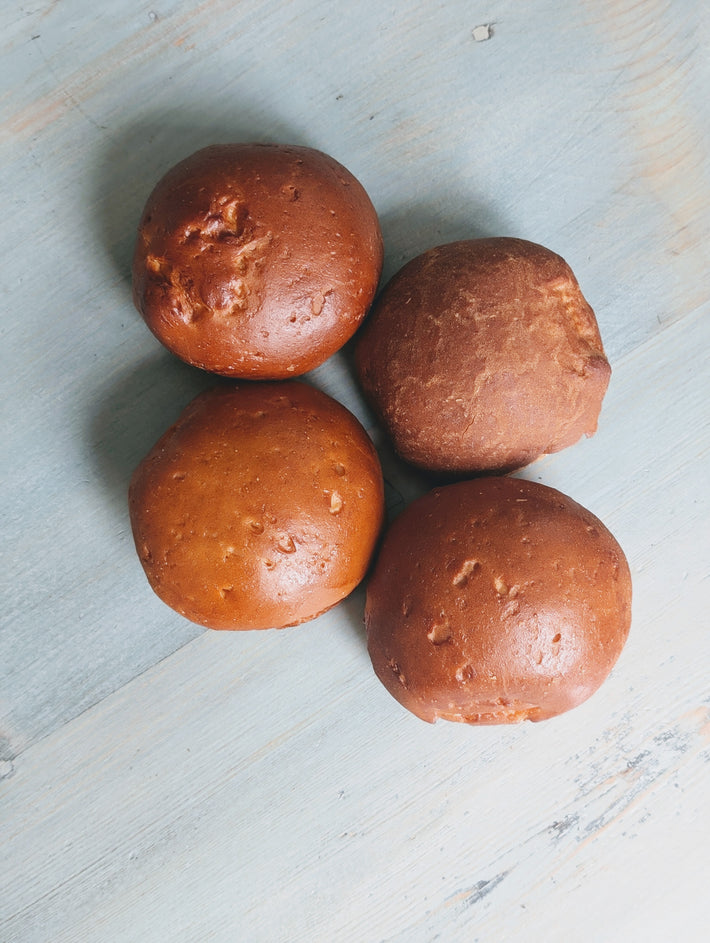 Gluten-Free Slow-Fermented Brioche Rolls (4-pack) on a light blue wooden surface.
