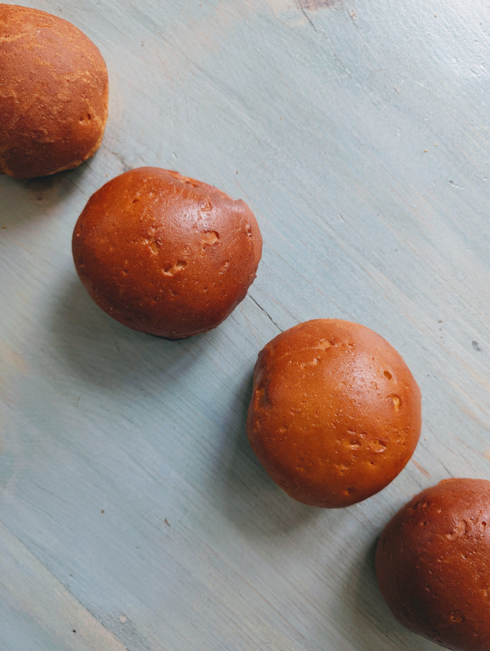 Gluten-Free Slow-Fermented Brioche Rolls on a light blue wooden surface.