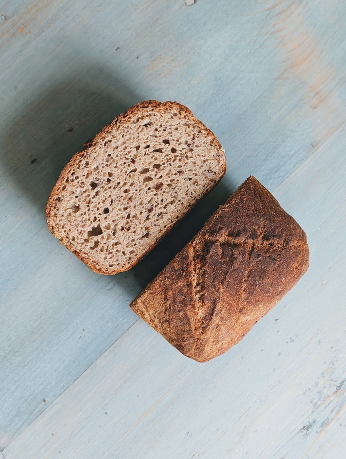 Sliced Gluten-Free Sourdough Loaf on a light blue wooden surface, showing its textured interior and crust.