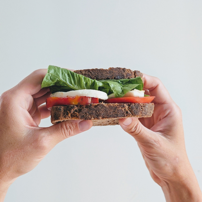 A sandwich with lettuce, tomato, and cheese between dark bread.