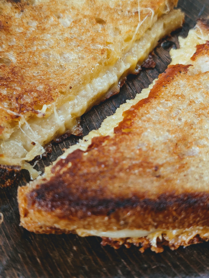 Close-up of a toasted grilled cheese sandwich with melted cheese oozing from between golden-brown slices.