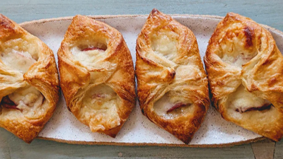 Overhead view of four ham and cheese croissants showing flaky golden layers and melted cheese on a speckled oval platter