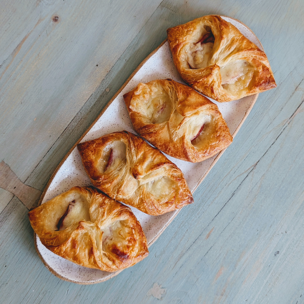 Four golden puff pastries with melted cheese on a speckled oval plate, top-down on a weathered blue wooden table.