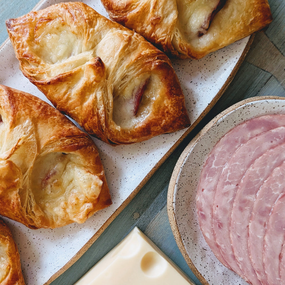 Four Ham & Cheese Croissants on a plate with sliced ham and cheese