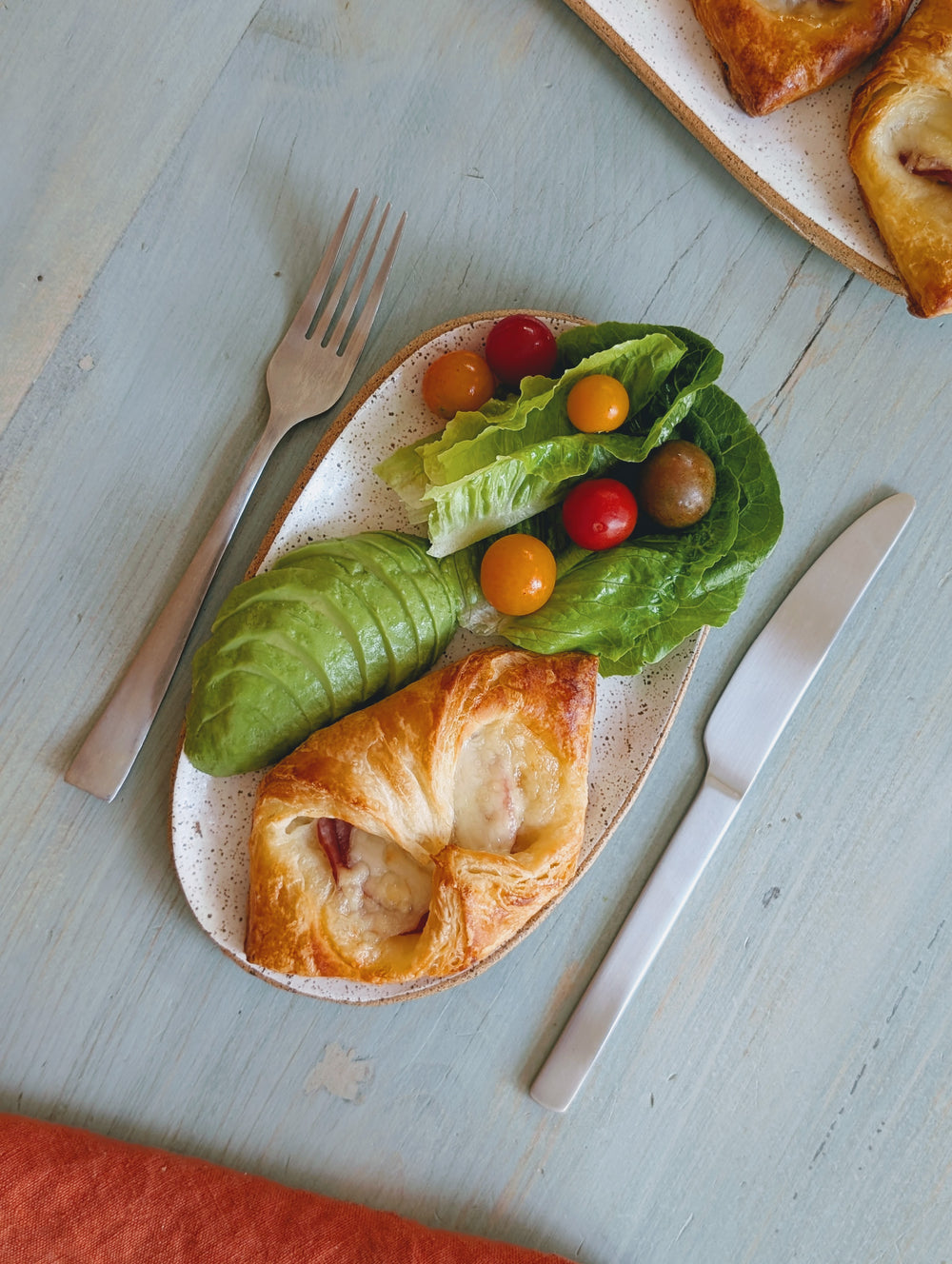 Ham & Cheese Croissant on a plate with greens and cherry tomatoes