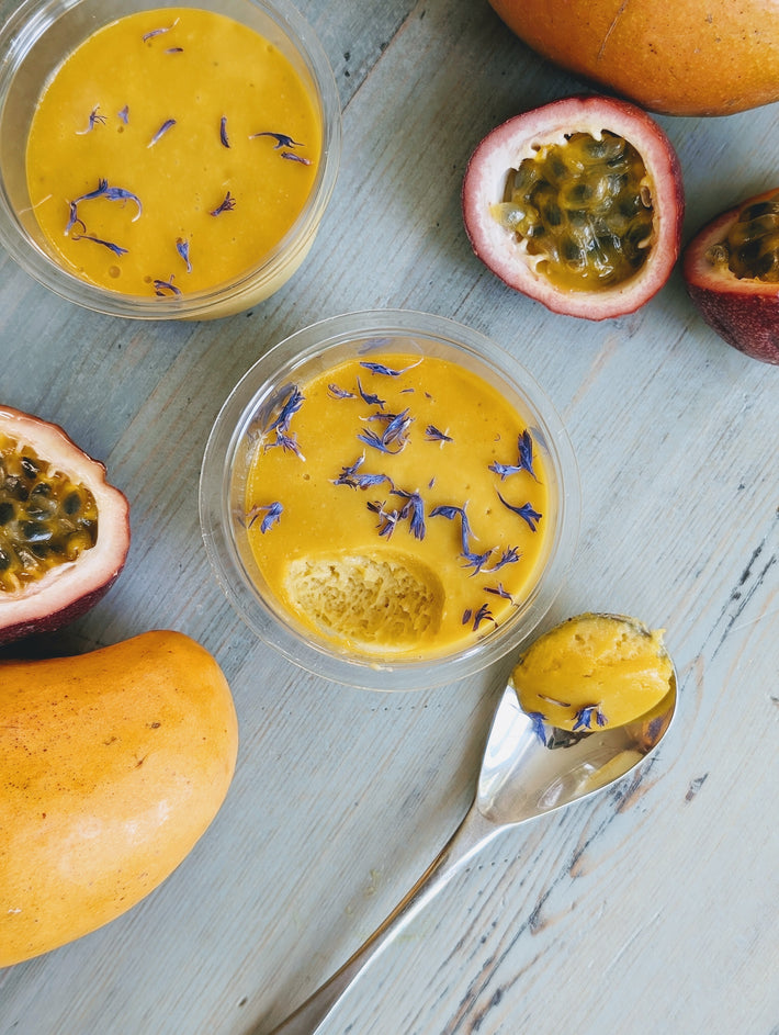 Mango and Passion Fruit Mousse with cornflower petals, surrounded by mango and passion fruits