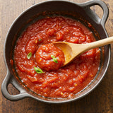 Top-down of Classic Marinara Sauce showing chunky tomato texture, wooden spoon, and basil on wood