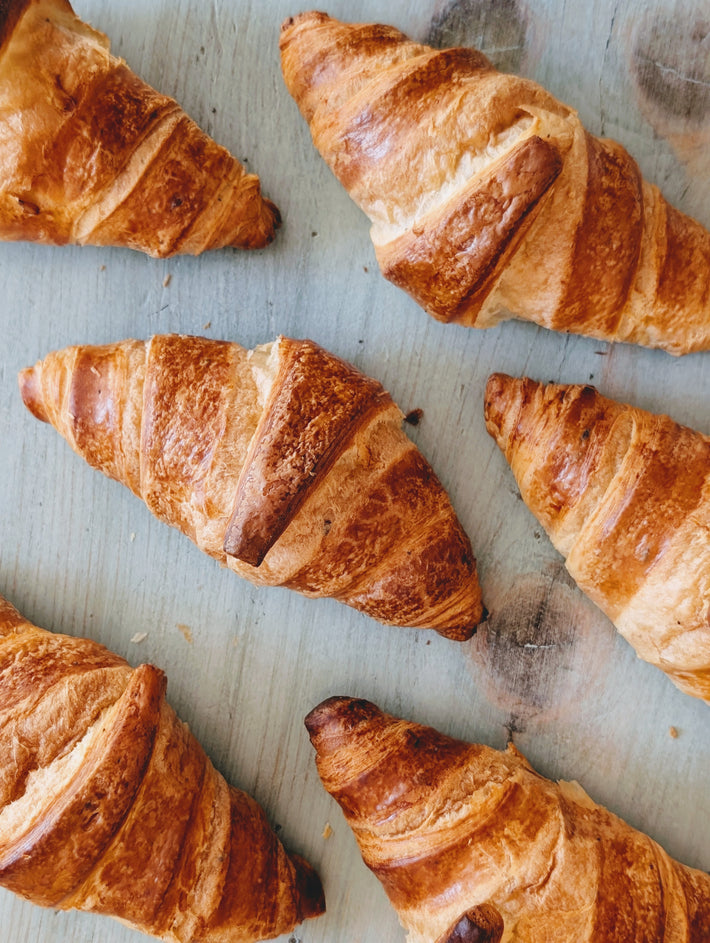 Golden flaky croissants arranged on a light-blue wooden board