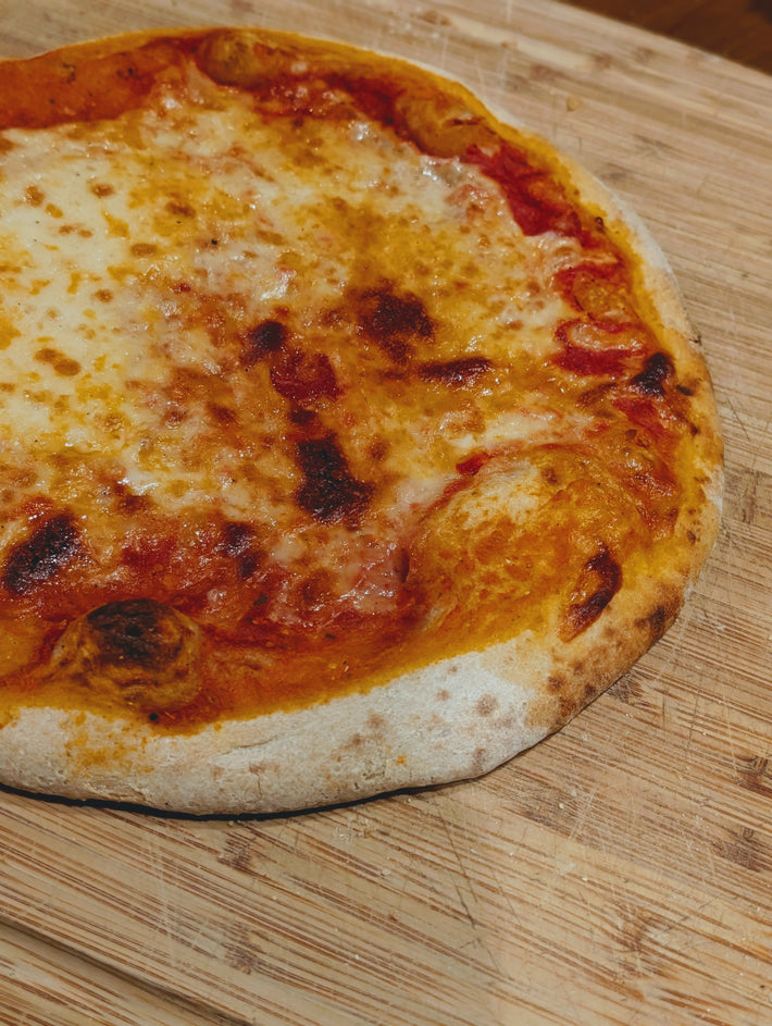 Slow-Fermented New York Cheese Pizza on a wooden cutting board.