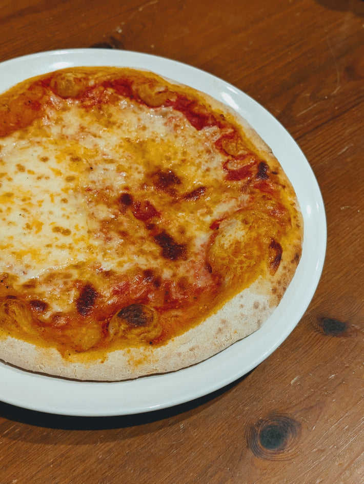 Slow-Fermented New York Cheese Pizza on a white plate, featuring melted cheese and a golden crust.