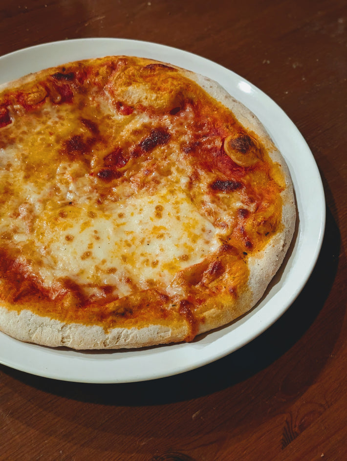Slow-Fermented New York Cheese Pizza on a white plate, with a golden crust and melted cheese.