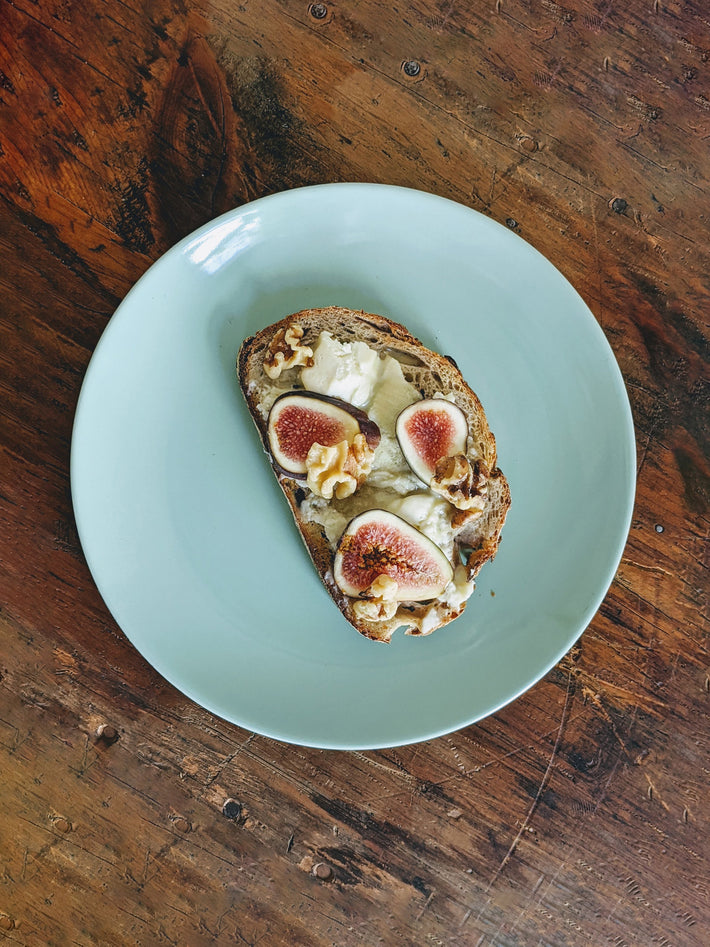 Sourdough toast topped with figs and walnuts on a light blue plate