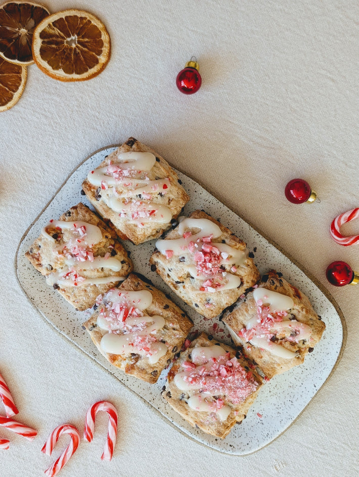 Festive baked goods with white icing and crushed peppermint on a platter, surrounded by candy canes.