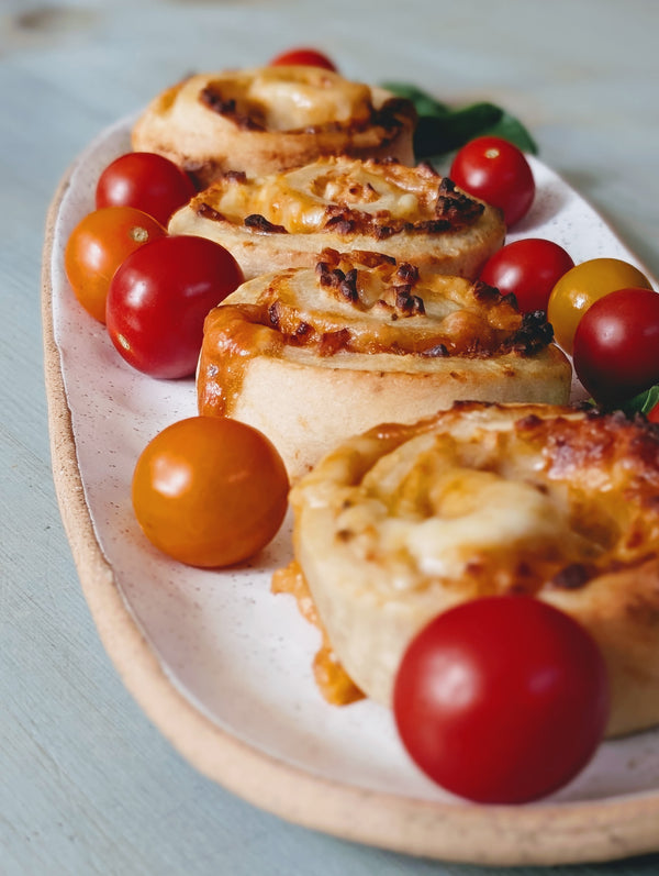 Rolls of pizza with cherry tomatoes on a white plate