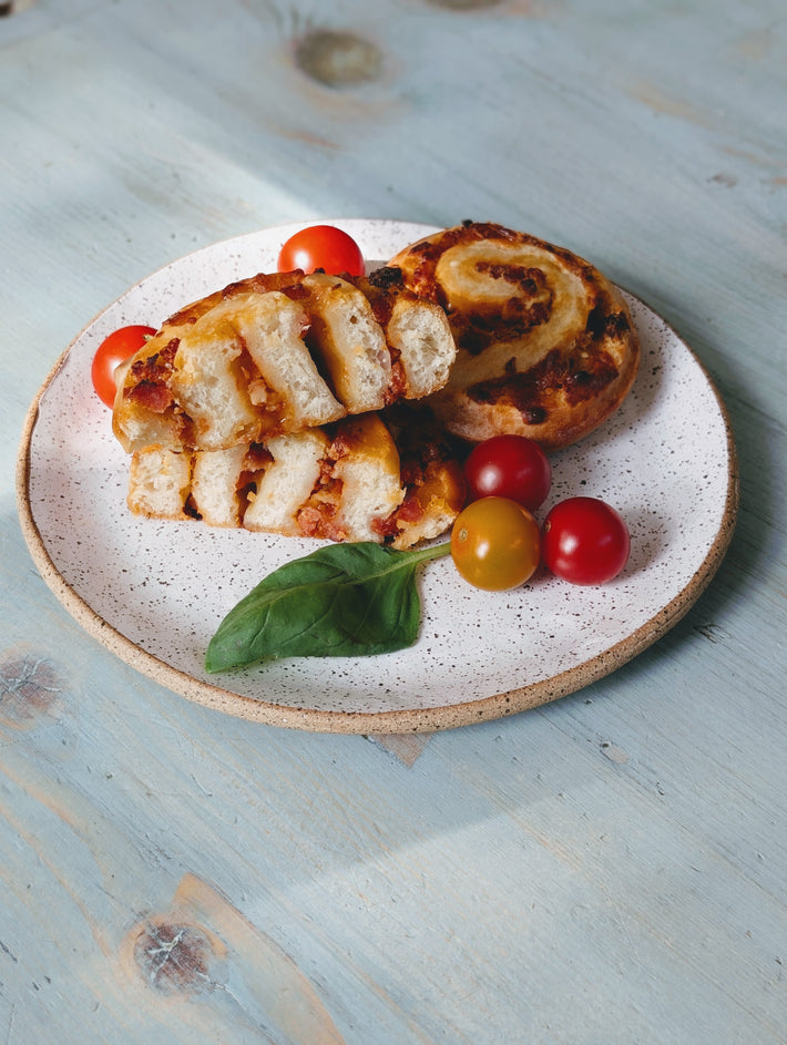 Sliced bread with cherry tomatoes on a speckled ceramic plate on a wooden surface