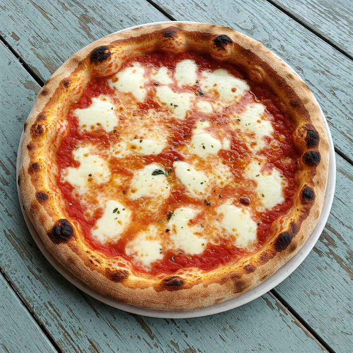 Wood-fired margherita pizza with blistered crust, melted mozzarella and tomato sauce on a blue-weathered wooden table