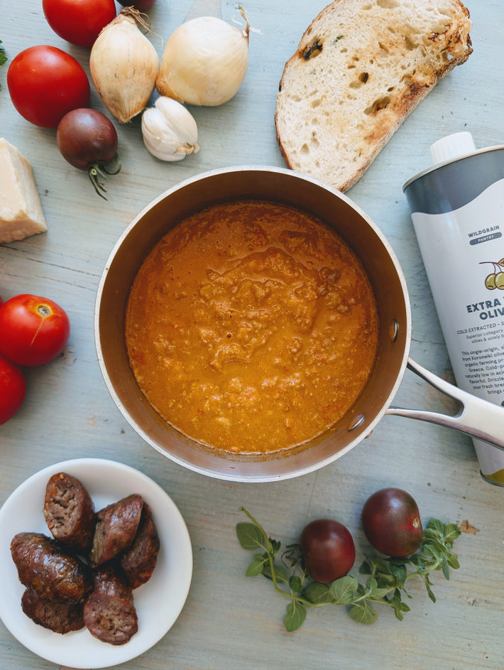 Pantry-style saucepan of tomato sauce with bread, tomatoes, garlic, sausage; can labeled WILDGRAIN PANTRY EXTRA OLIVE