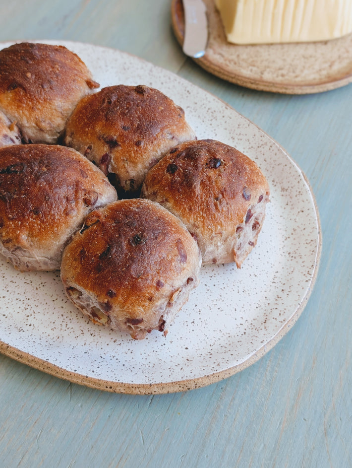 Tear & Share Cranberry-Pecan Rolls (6-pack) on a speckled plate with butter in the background.