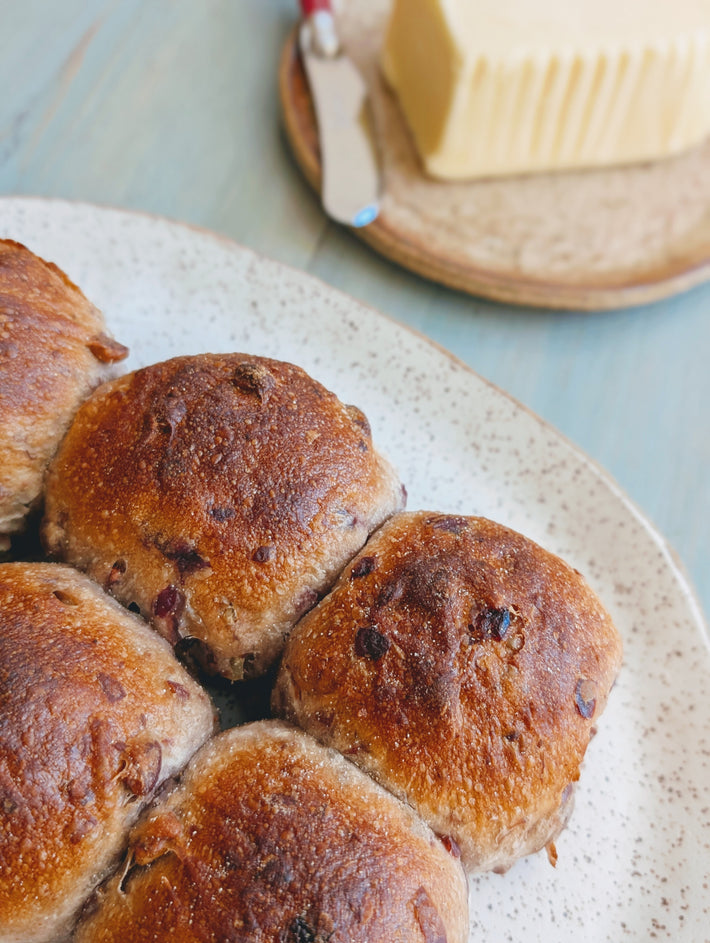 Freshly baked cranberry-pecan rolls on a plate with butter in the background.