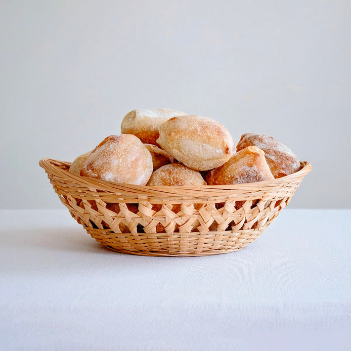 A basket of sourdough rolls, freshly baked and golden brown.